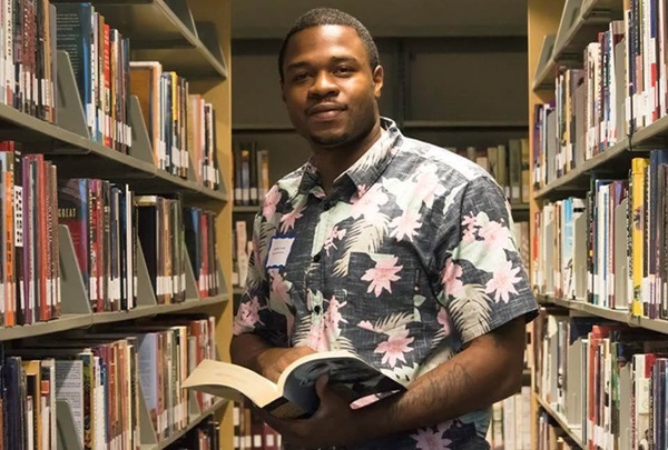 Student in library standing with book